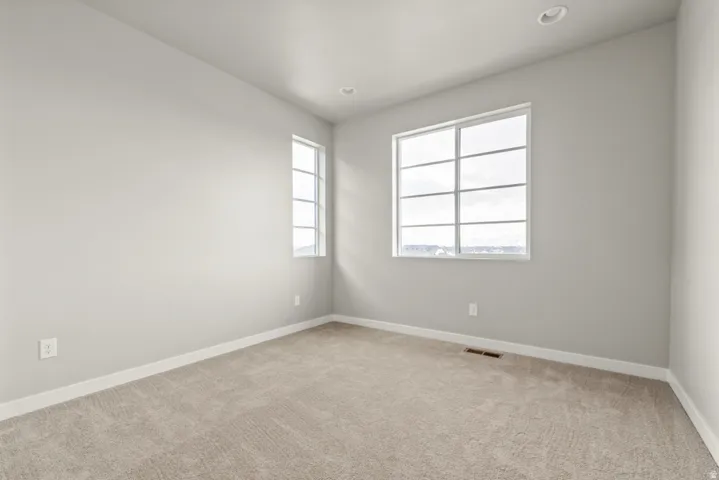 Carpeted interior space featuring neutral wall tones and two distinct windows