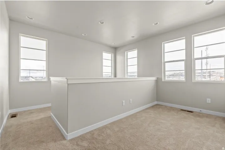 Open loft area featuring neutral-toned carpeting and light gray walls