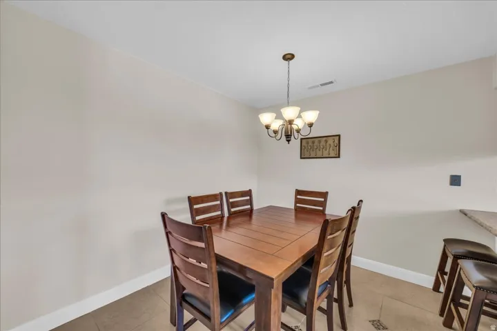 Dining area featuring neutral wall tones, tile flooring, and a bronze chandelier