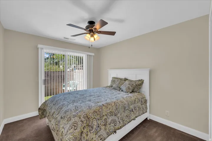 Neutral-toned interior featuring a ceiling fan with integrated lighting, a white paneled headboard, and rich brown carpeting