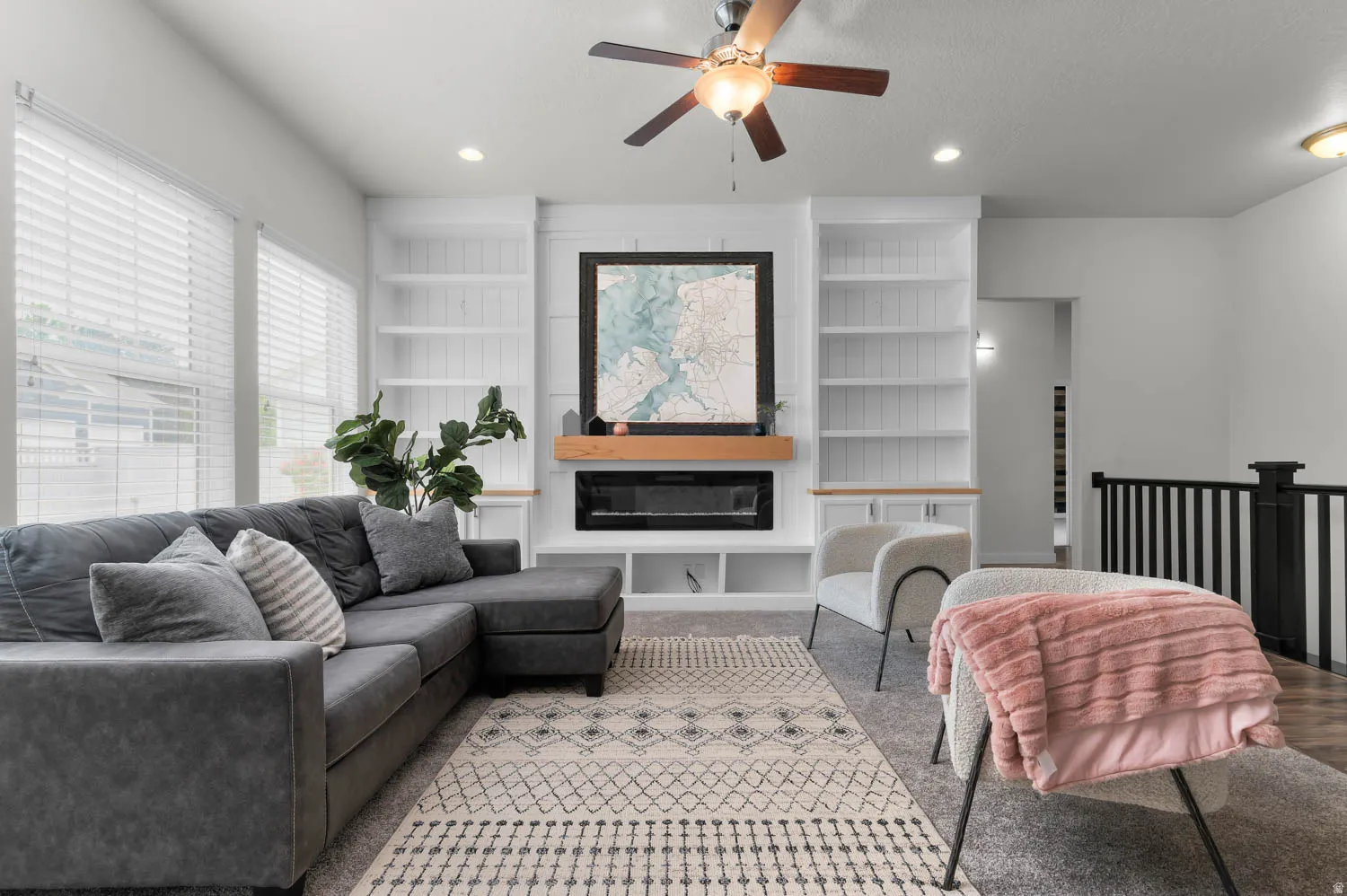 Bright living space featuring a built-in electric fireplace with a wood mantle, flanked by custom white cabinetry and shelving