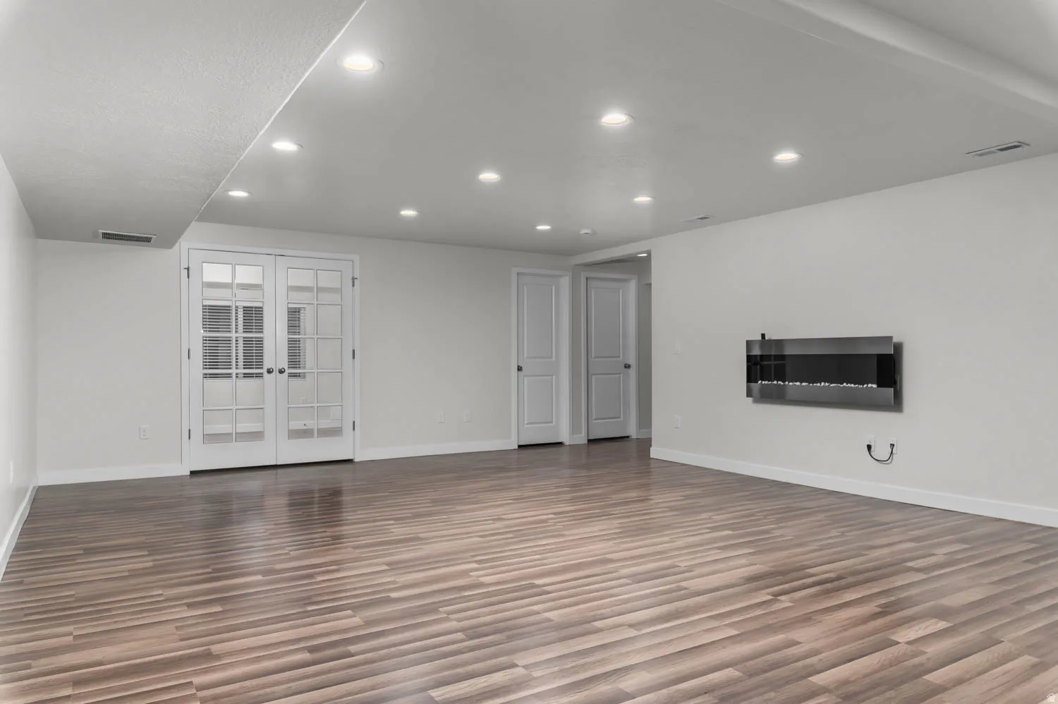 Spacious room featuring wood-finish flooring, recessed lighting, and white walls
