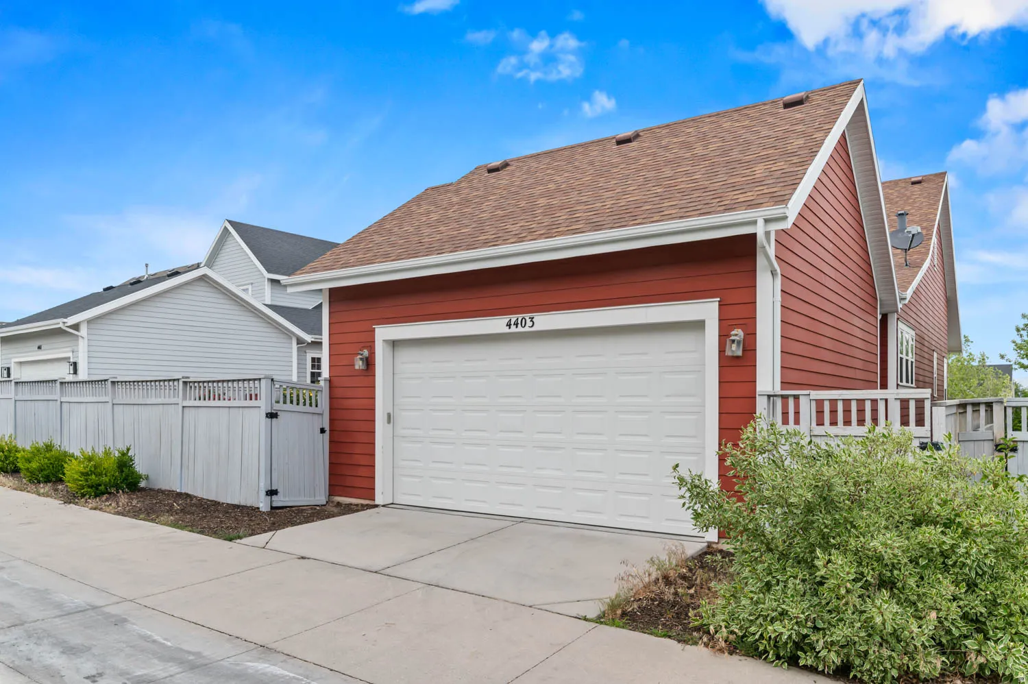 Red siding exterior featuring a white garage door, asphalt shingle roof, and white trim