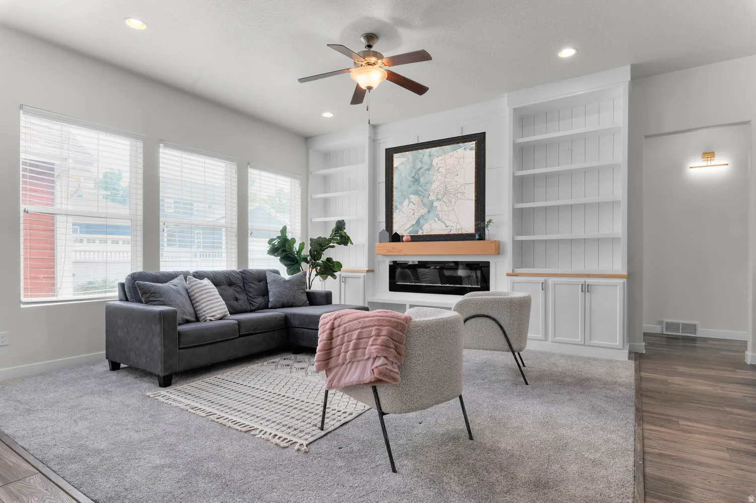 Living area featuring a built-in fireplace with a wood mantle, custom shelving, recessed lighting, and a ceiling fan