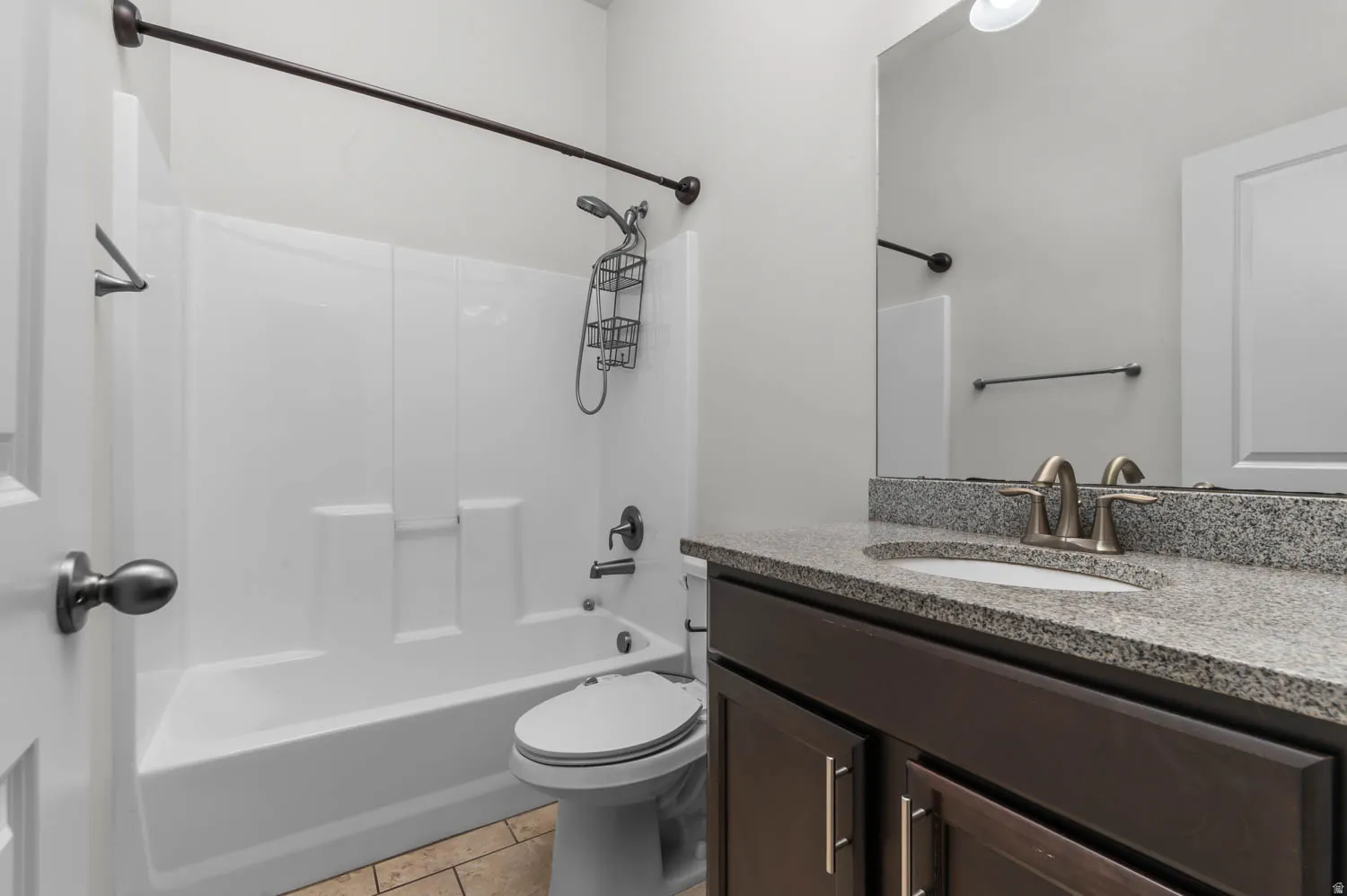 Bathroom featuring a white tub/shower combination, dark wood-finish vanity with a granite countertop, and tile flooring