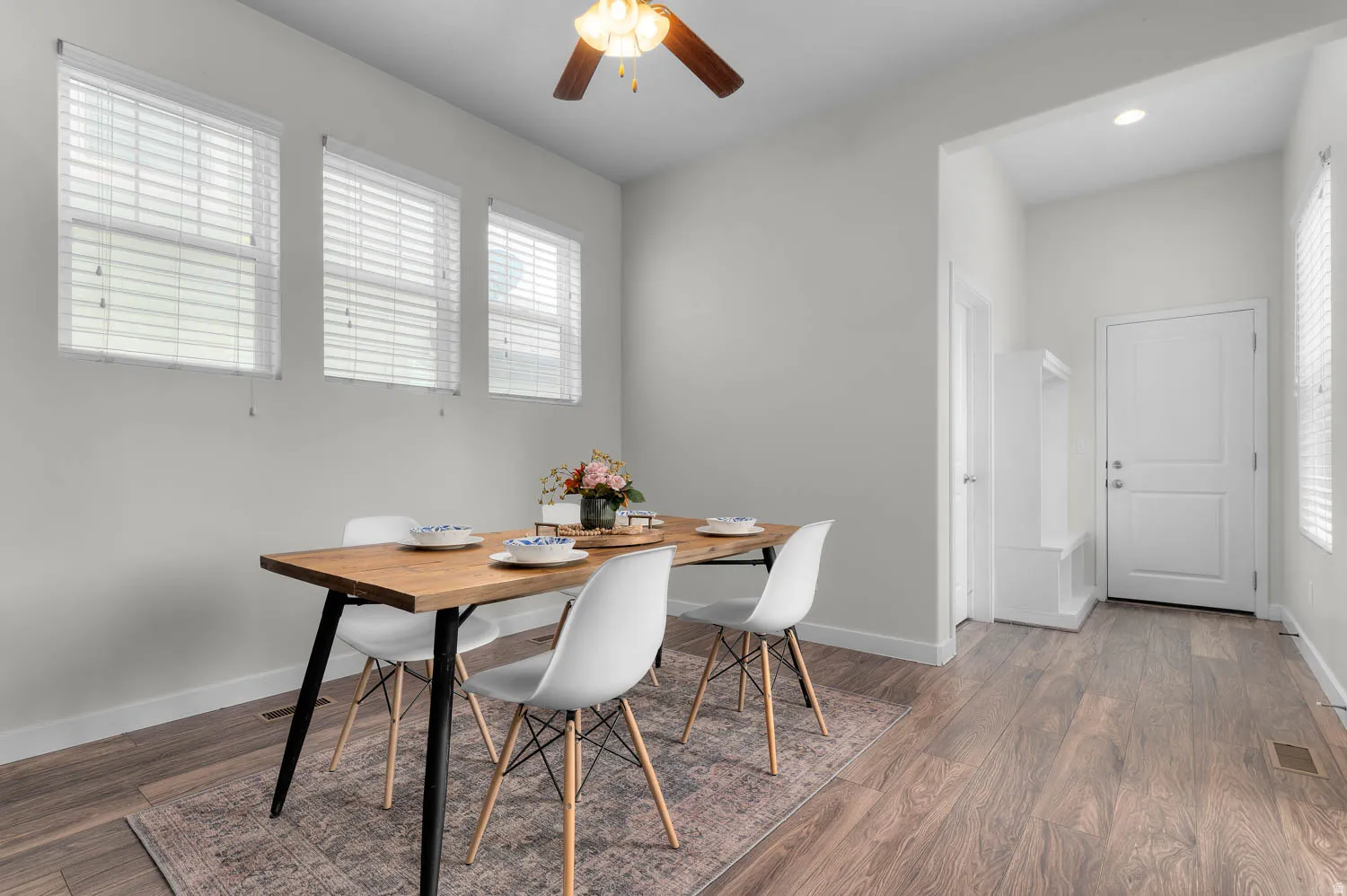 Dining area featuring wood-finish flooring, a ceiling fan, and three windows with blinds