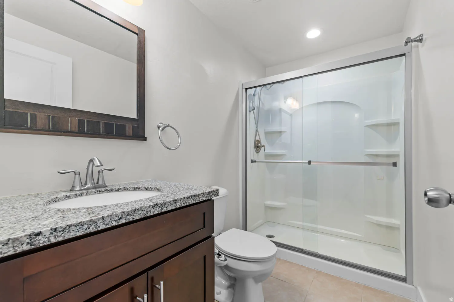 Bathroom vanity featuring a granite countertop, undermount sink, and wood-finish cabinetry
