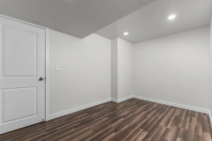 Room featuring wood-finish flooring, white baseboards, and neutral wall paint