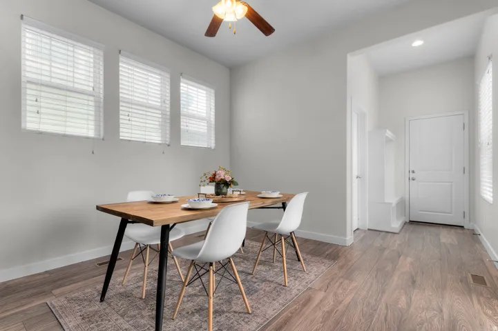 Dining area featuring wood-finish flooring, a ceiling fan, and three windows with blinds