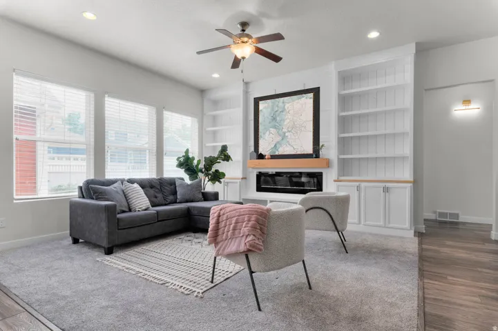 Living area featuring a built-in fireplace with a wood mantle, custom shelving, recessed lighting, and a ceiling fan