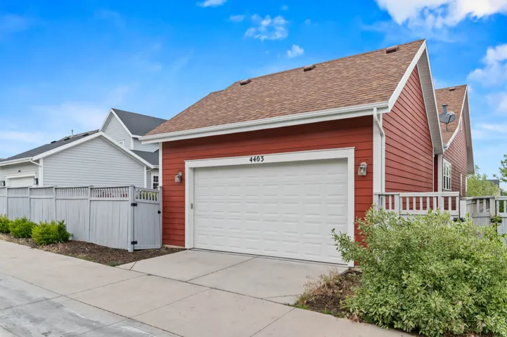 Red siding exterior featuring a white garage door, asphalt shingle roof, and white trim