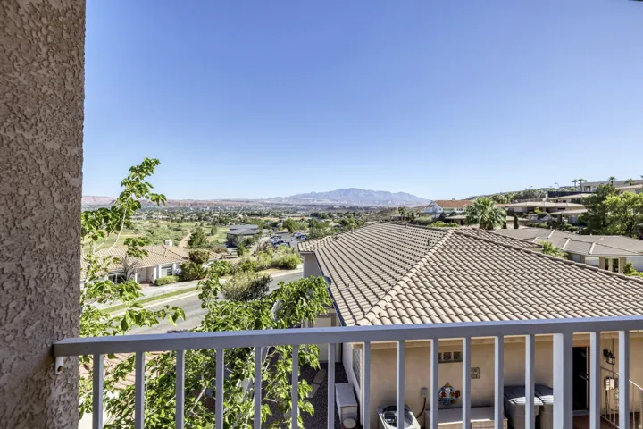 Balcony with metal railing providing expansive scenery of distant mountains, residential properties, and a golf course