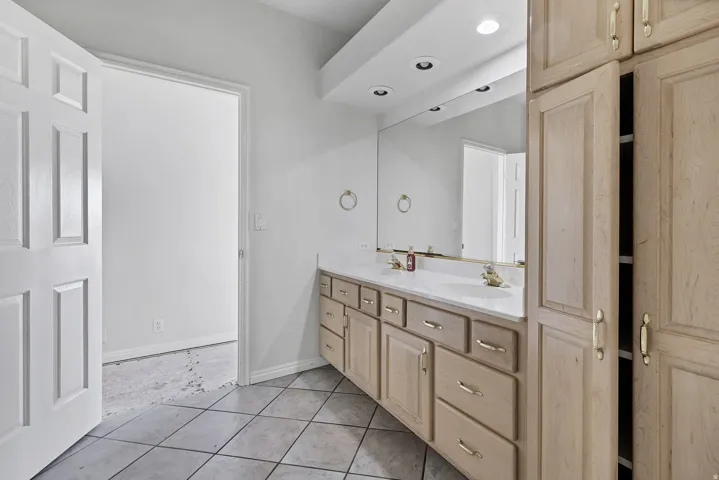 Bathroom featuring a dual vanity with a large mirror, integrated sinks, recessed lighting, and extensive built-in storage cabinetry