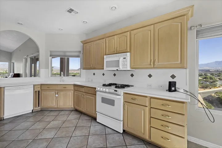 Kitchen featuring blonde wood cabinetry, white countertops, tile backsplash, and a built-in microwave