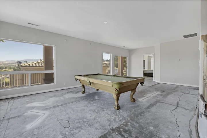 Expansive open room featuring large picture windows, a balcony with white railings, and an entry to an additional room