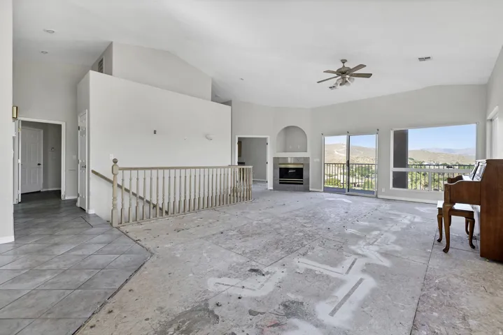 Spacious living area featuring high vaulted ceilings and a built-in fireplace with a tiled surround