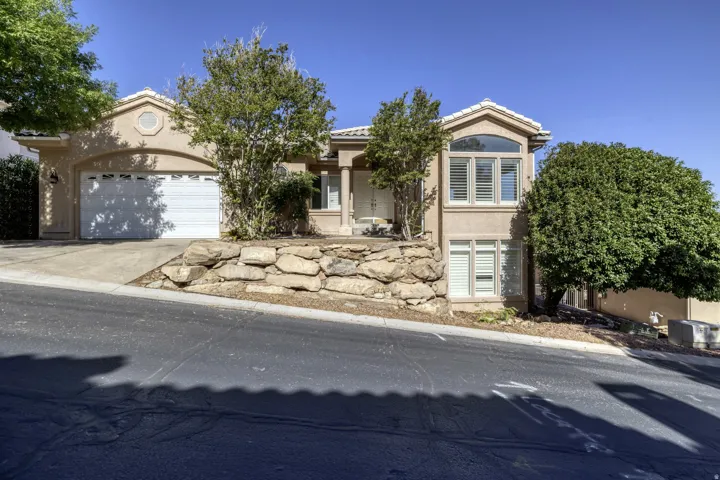 Stucco exterior residence featuring a two-car garage, arched entryways, and prominent window shutters