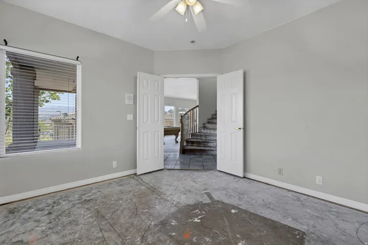 Interior space with light gray walls, a ceiling fan, and a window featuring horizontal blinds