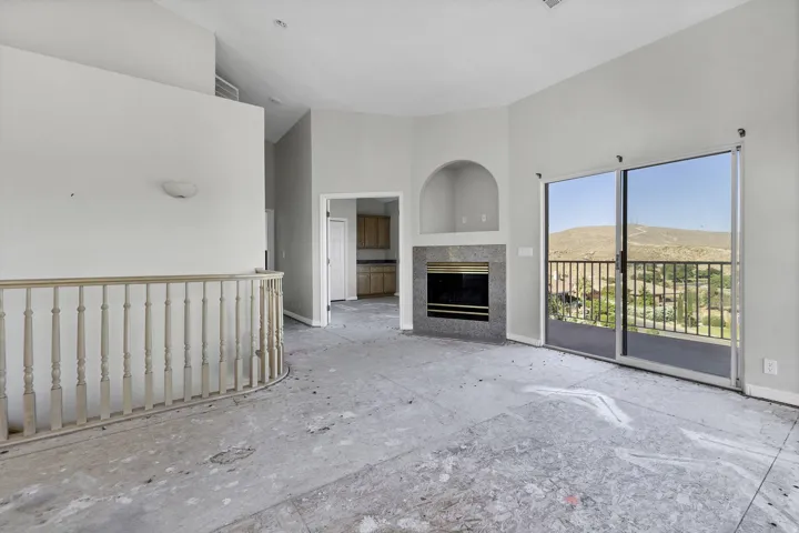 Spacious living area featuring a fireplace with a stone surround, an arched alcove, and a built-in wall sconce