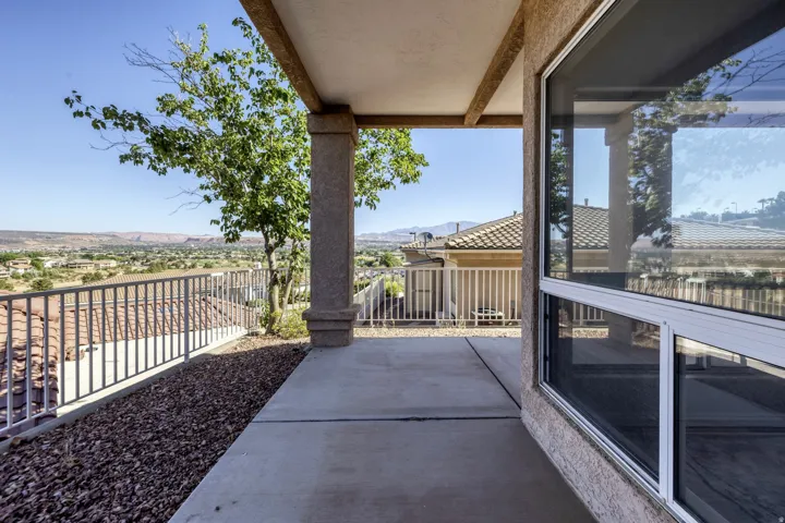 Covered patio with concrete flooring, accented by a decorative column and a metal railing