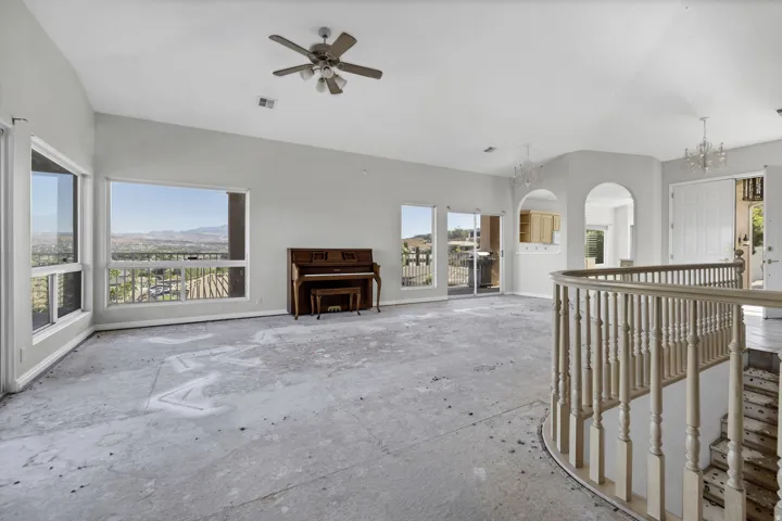 Expansive living space featuring vaulted ceilings, multiple large windows, and a sliding glass door providing abundant natural light