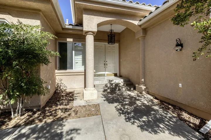 Entryway featuring an arched portico with a columnar support, dual pane windows, exterior wall sconce, and a hanging lantern fixture above the double entry doors