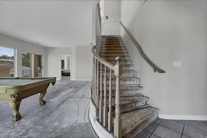 Curved staircase with wood balusters and handrail, gray wall paneling, and a large window array