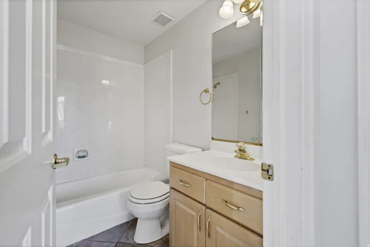 Bathroom featuring a wood-finish vanity with a white countertop, an integrated sink, and a framed mirror