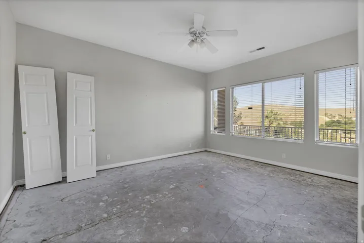 Spacious room featuring multiple windows with horizontal blinds, a ceiling fan, and baseboard trim