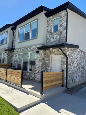 Modern multi-story exterior featuring a stacked stone facade and light stucco accents