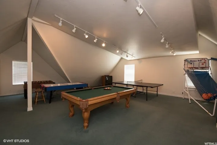 Spacious bonus room featuring sloped ceilings, track lighting, and soft green carpeting