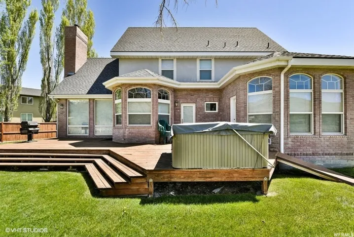 Expansive rear exterior featuring a multi-level wood deck, a brick facade, and a prominent bay window with arched upper panes