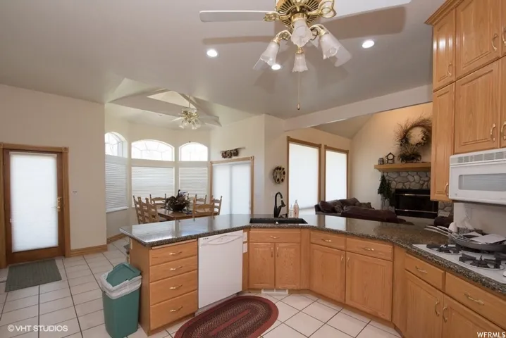 Open-concept kitchen featuring oak cabinetry, granite-style countertops, and a built-in gas range