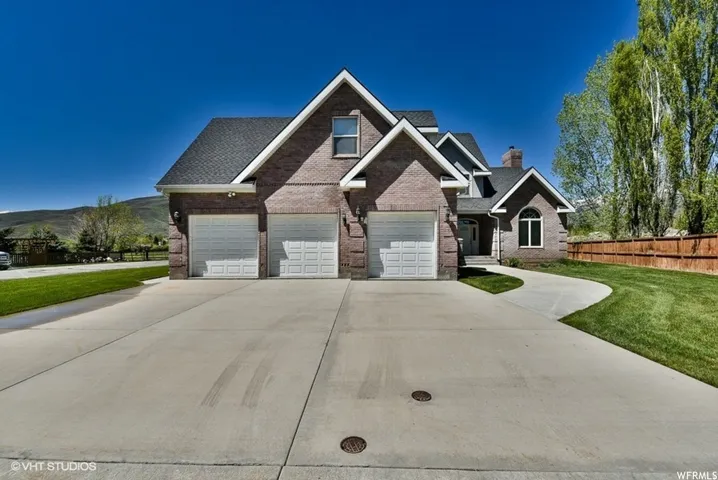 Brick exterior residence featuring a three-car garage and a curved concrete driveway