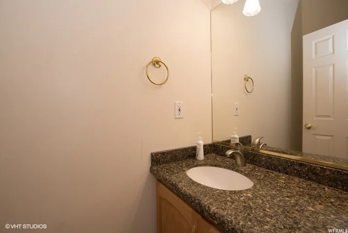 Vanity featuring a stone-look countertop with an undermount sink, brushed nickel faucet, and a large wall-mounted mirror