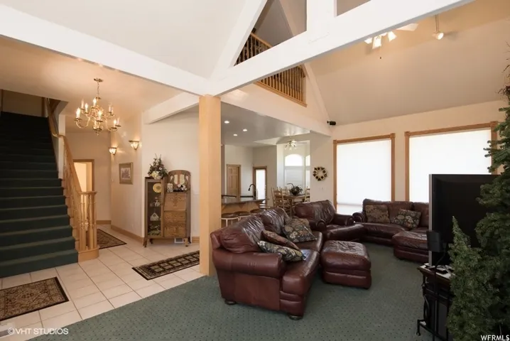 Spacious main living area featuring a vaulted ceiling with exposed beams, wood-trimmed windows, and an open concept layout