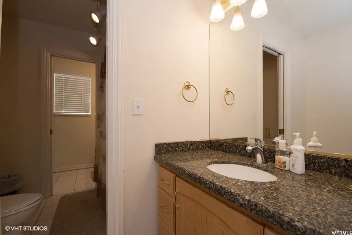 Bathroom vanity featuring a speckled countertop, integrated sink, and a large wall-mounted mirror