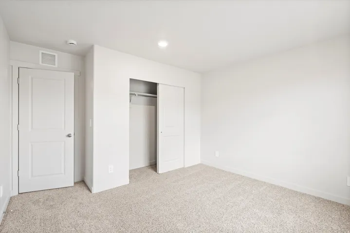 **DISLCAIMER** Interior package may vary. Carpeted room with white walls, a two-panel interior door, and a closet with sliding doors