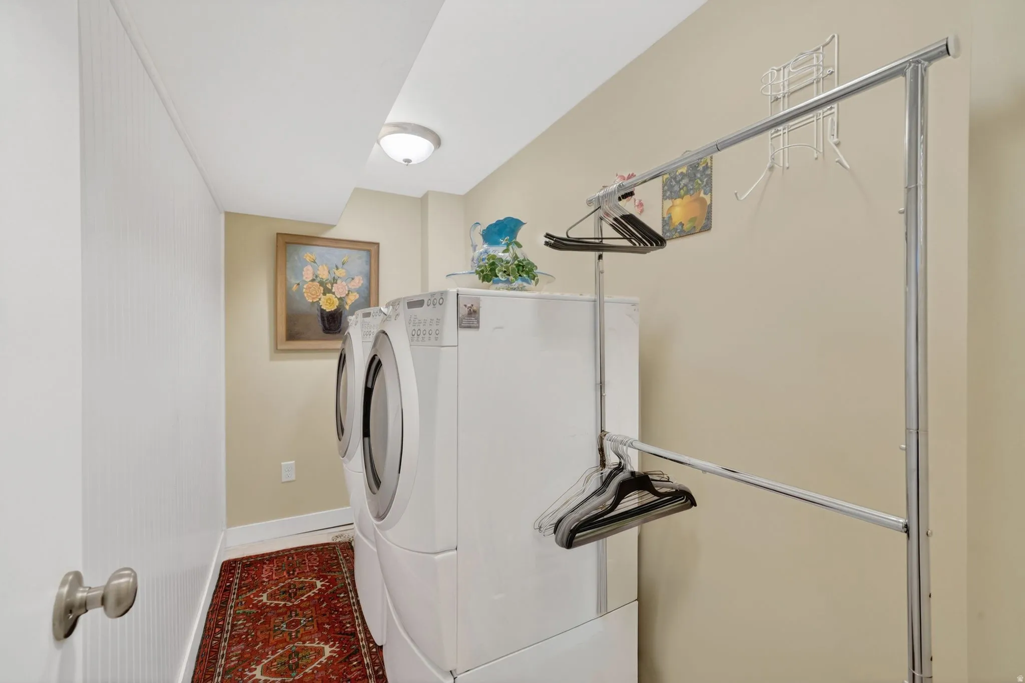 Dedicated laundry area featuring included  washer and dryer, wall paneling, and neutral wall paint