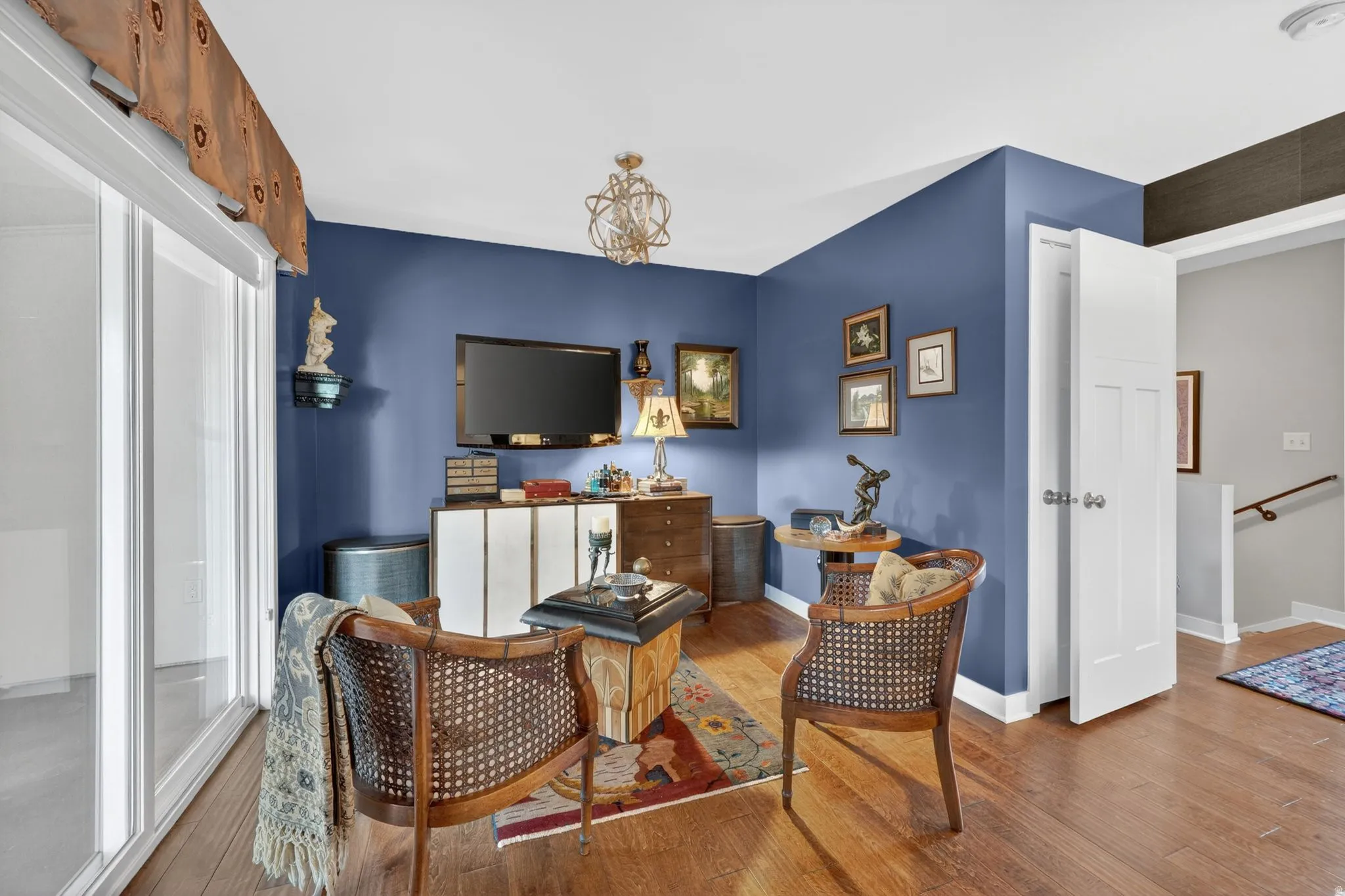 Primary bedroom seating area featuring engineered hardwood flooring, a contemporary chandelier