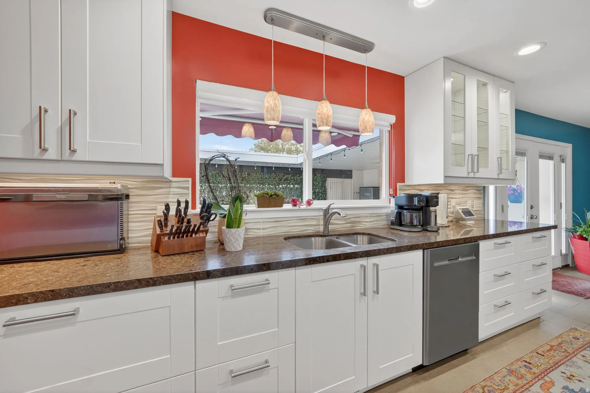 Kitchen featuring white modern cabinetry, dark quartz countertops, a stainless steel double basin sink, and a built-in dishwasher