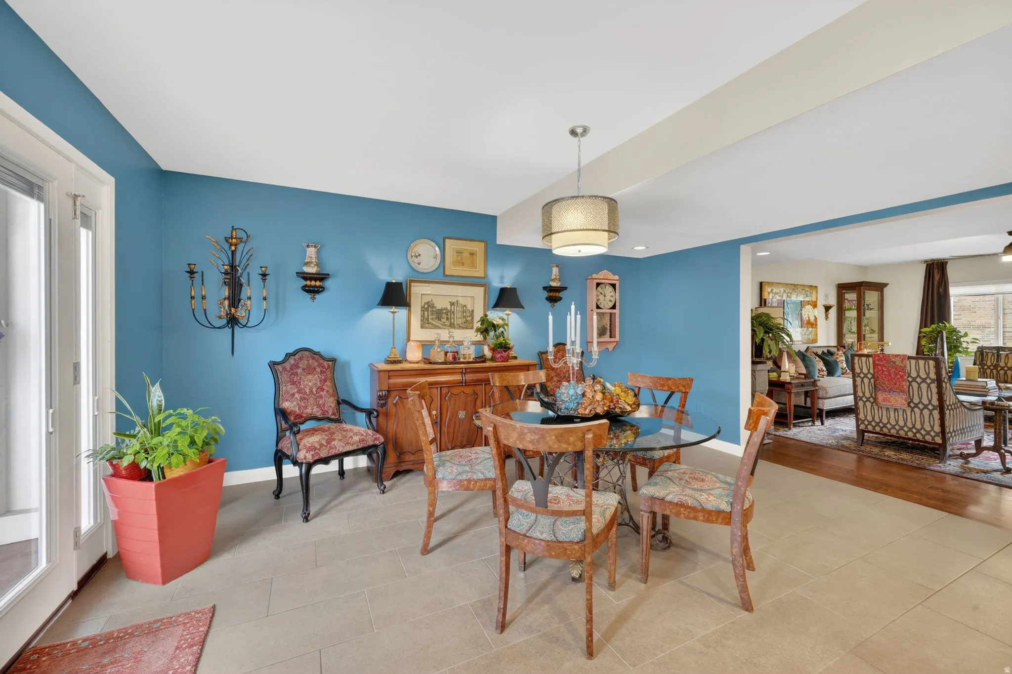 Dining area featuring a contemporary drum pendant light fixture, tile flooring, and a wide entryway that leads out to the private patio area
