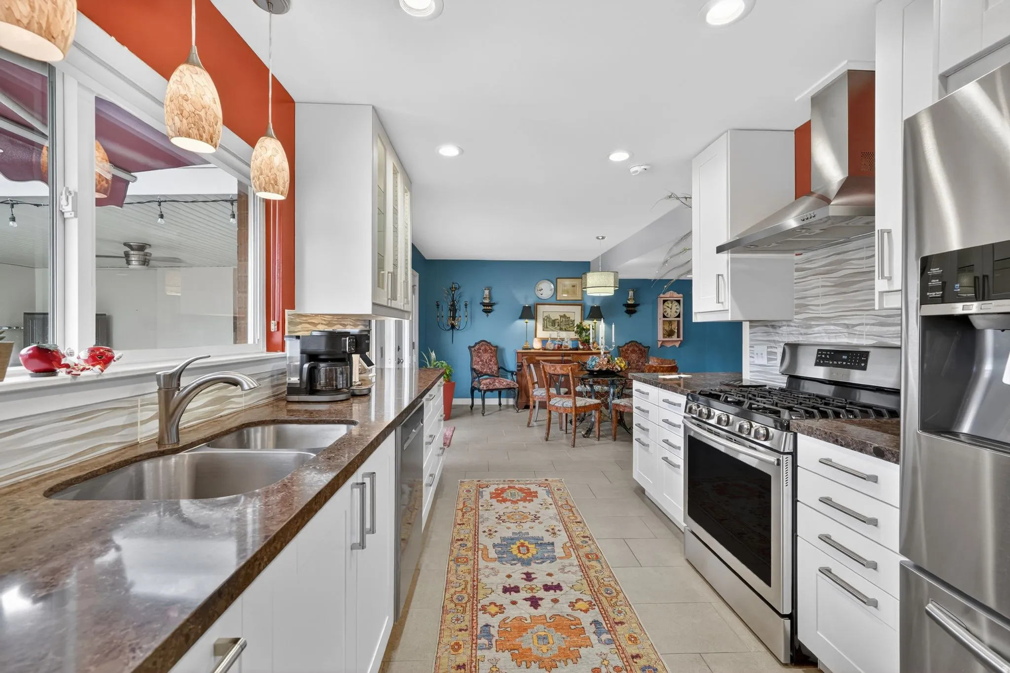 Modern kitchen featuring white cabinetry, stainless steel appliances, a double basin sink, and pendant lighting