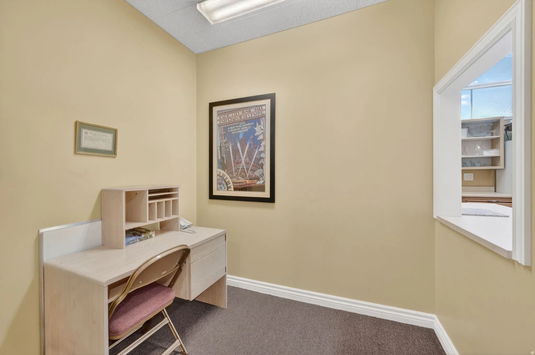 Club house office area featuring a service window, drop ceiling with fluorescent lighting, and neutral-toned walls