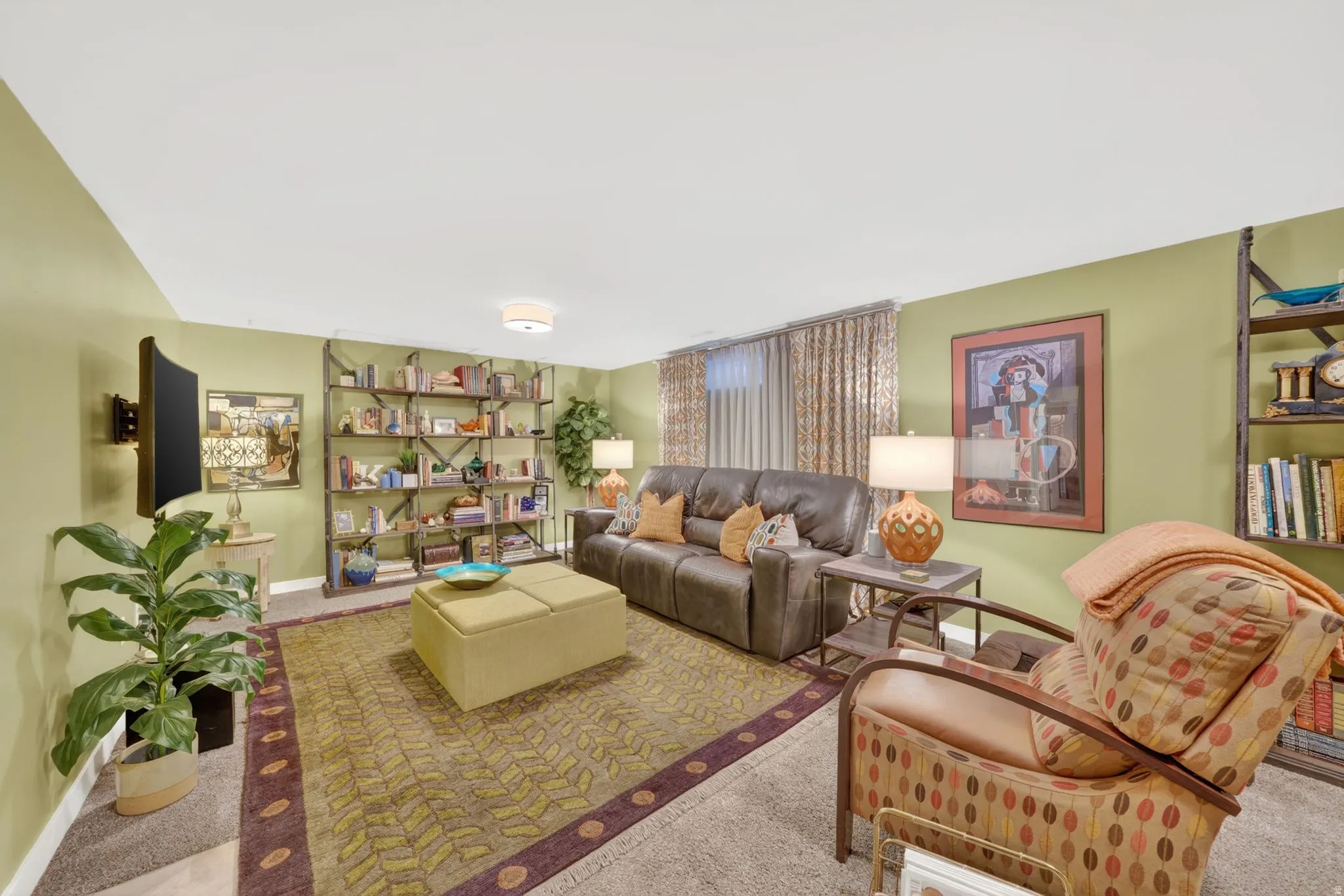 Carpeted recreational area featuring light green walls, a flush-mount ceiling light fixture, and a built-in wall-mounted television bracket