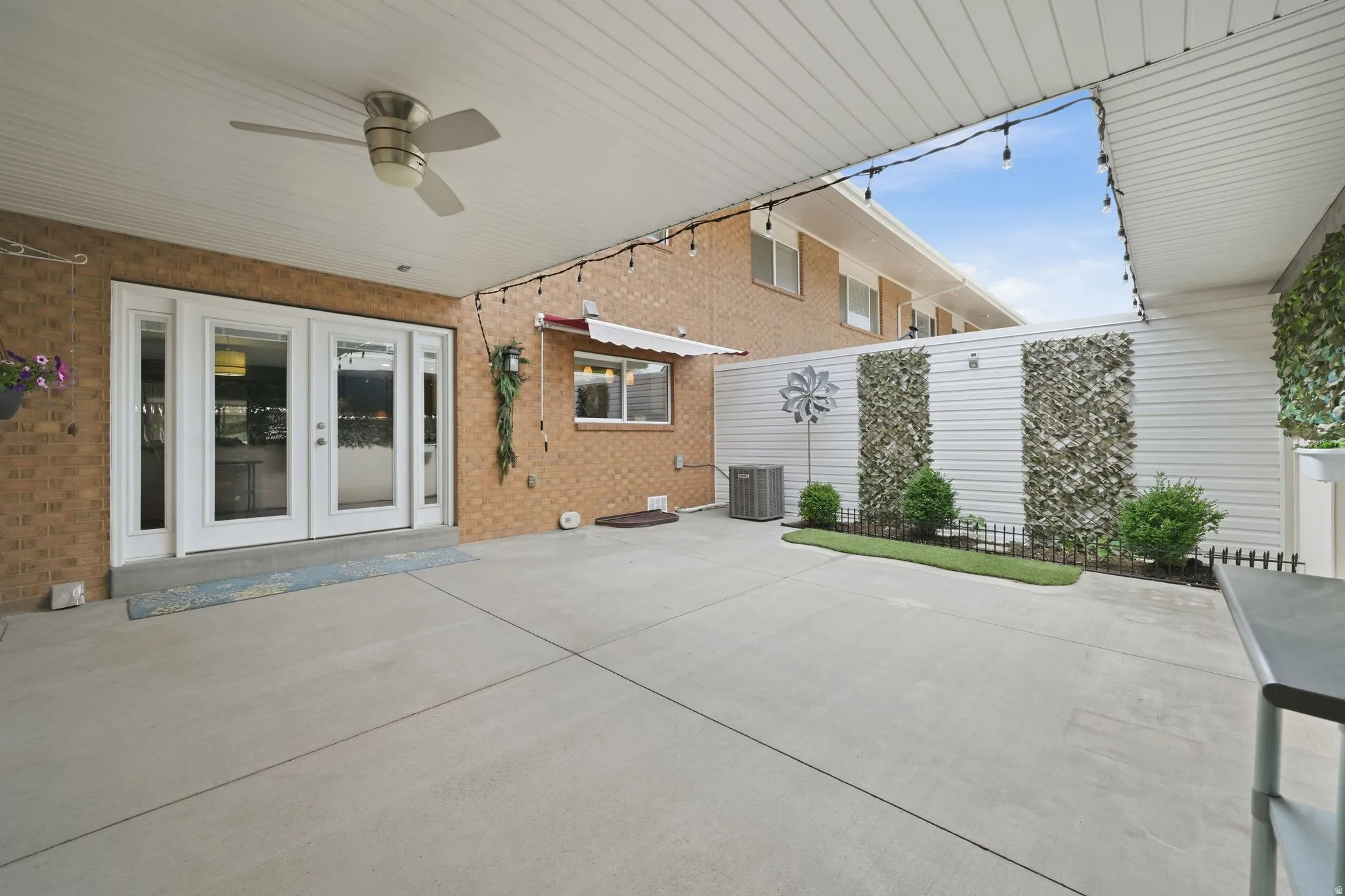 Expansive covered patio featuring a ceiling fan, string lights, and concrete flooring, and included mounted TV