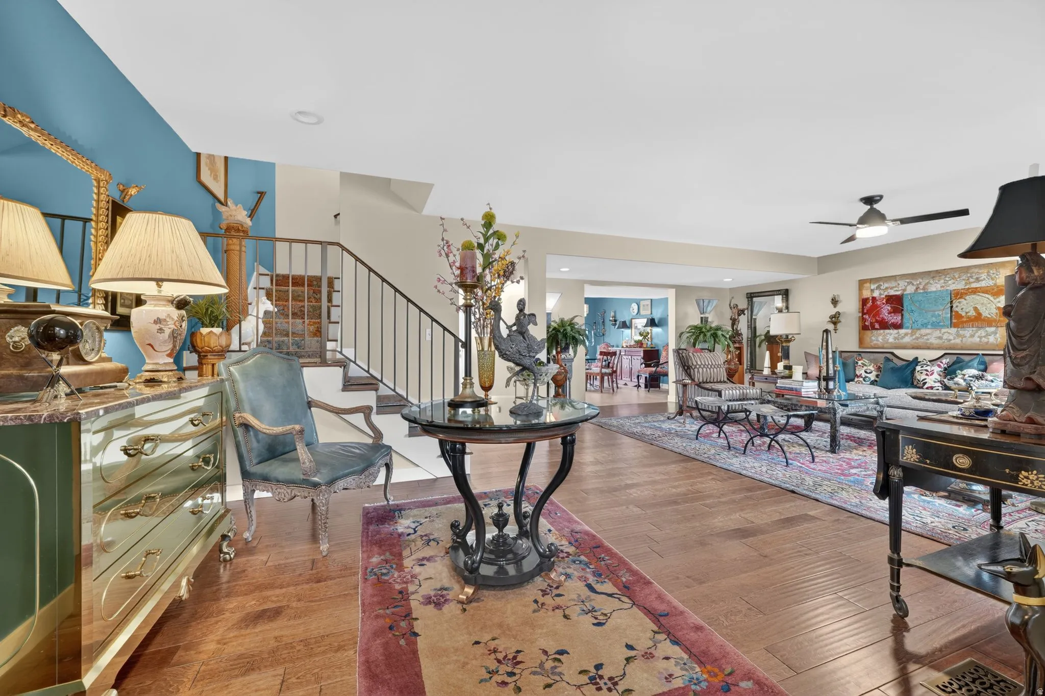Open-concept living space featuring engineered hardwood flooring, a contemporary ceiling fan, and a staircase with custom railing