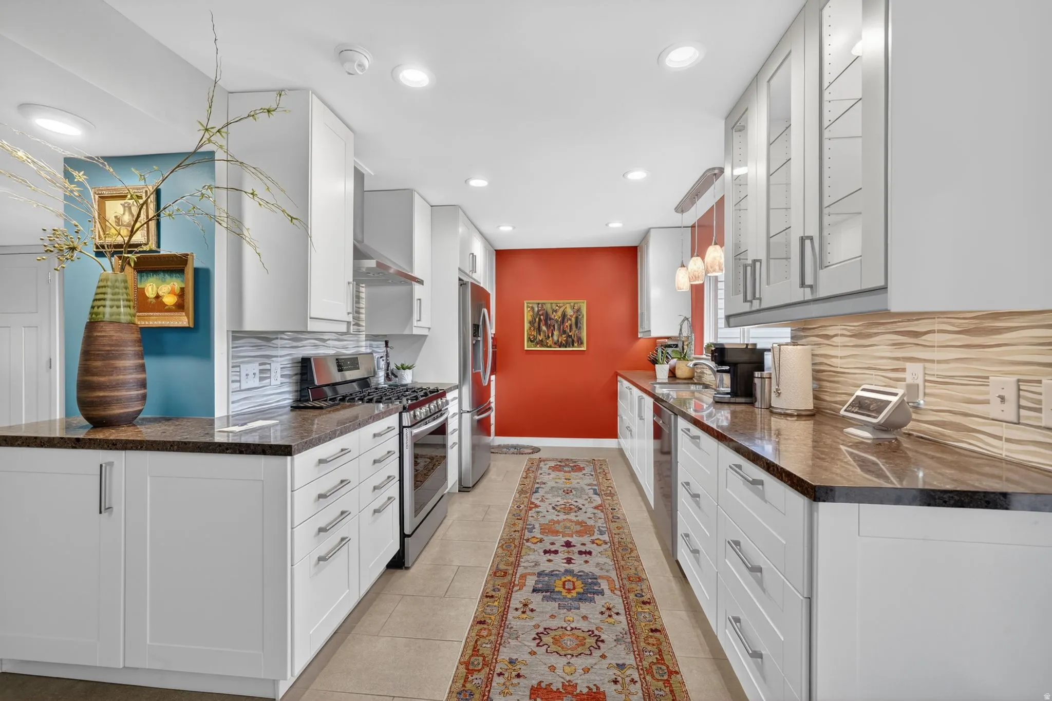 Galley kitchen featuring white cabinetry, dark quartz countertops, included stainless steel appliances, and tile flooring