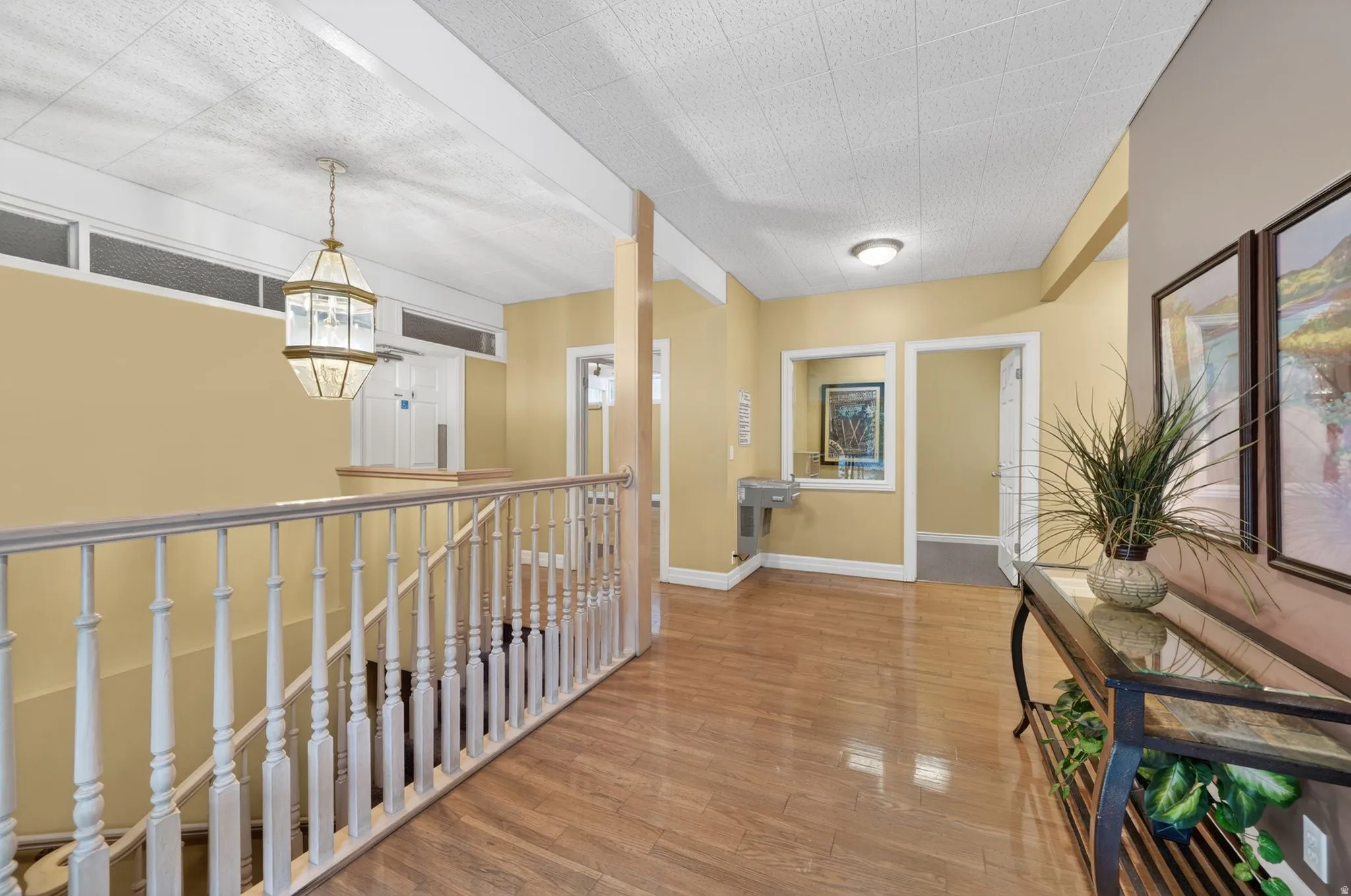 Club House interior hallway featuring hardwood-finish flooring extending throughout the upper landing with white baluster railing