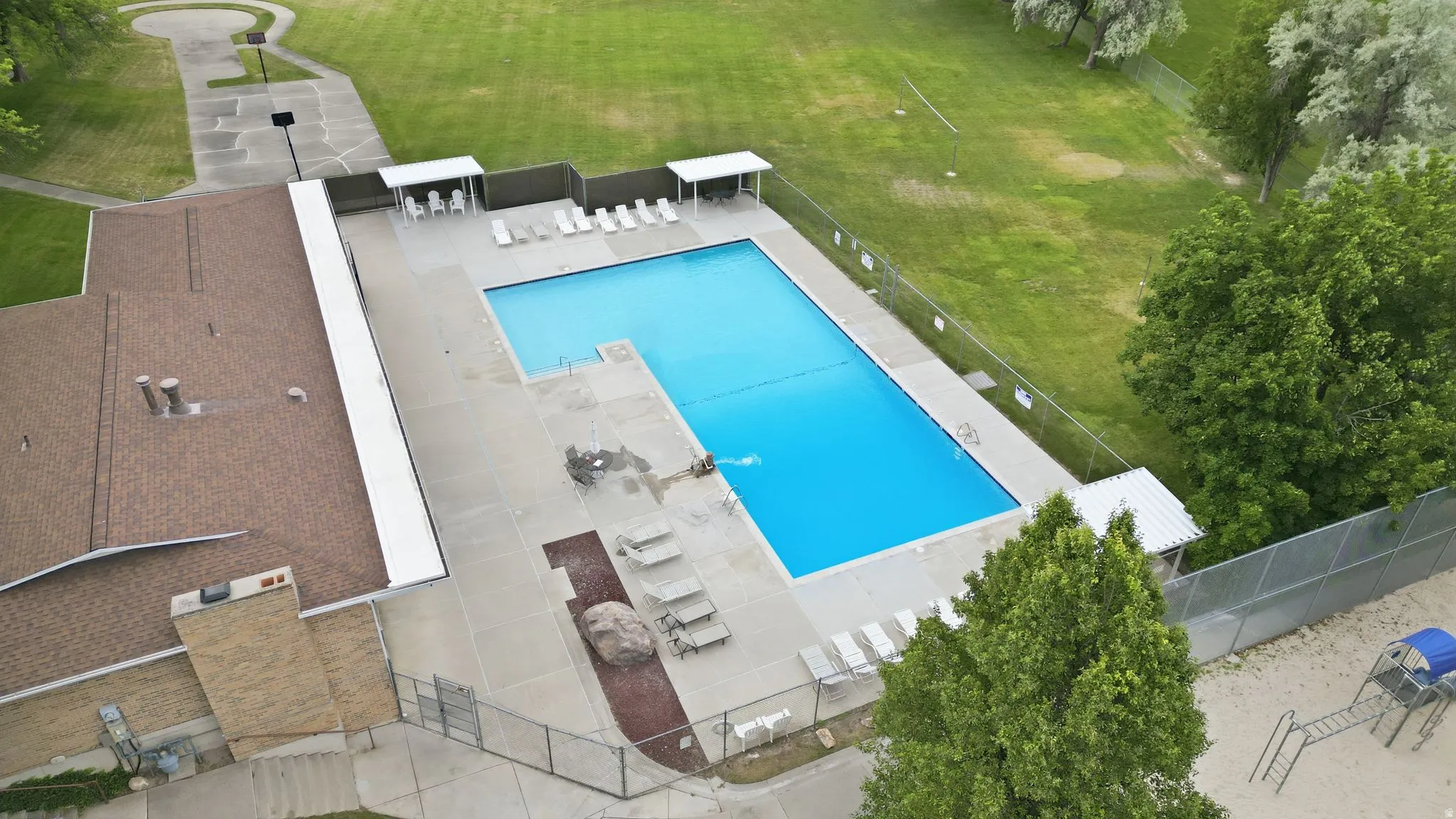 Expansive outdoor swimming pool with surrounding concrete decking and lounge chairs